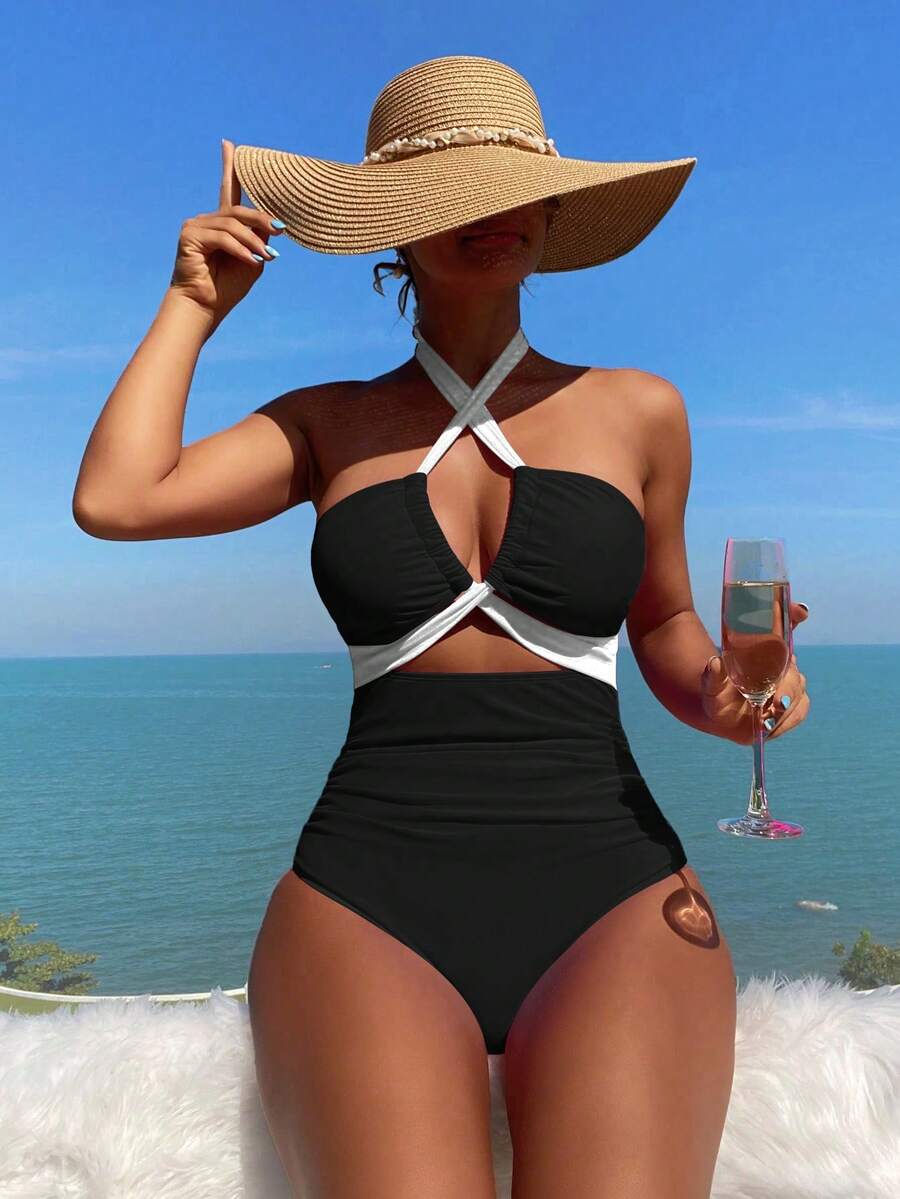 Mujer luciendo un traje de baño entero negro y blanco con escote halter cruzado frente al mar.