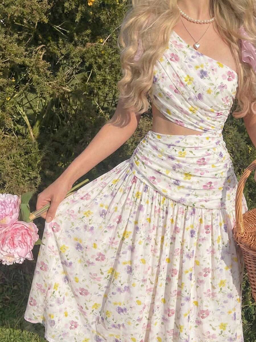 Mujer en un jardín luciendo un vestido blanco con estampado floral, escote asimétrico y falda midi.