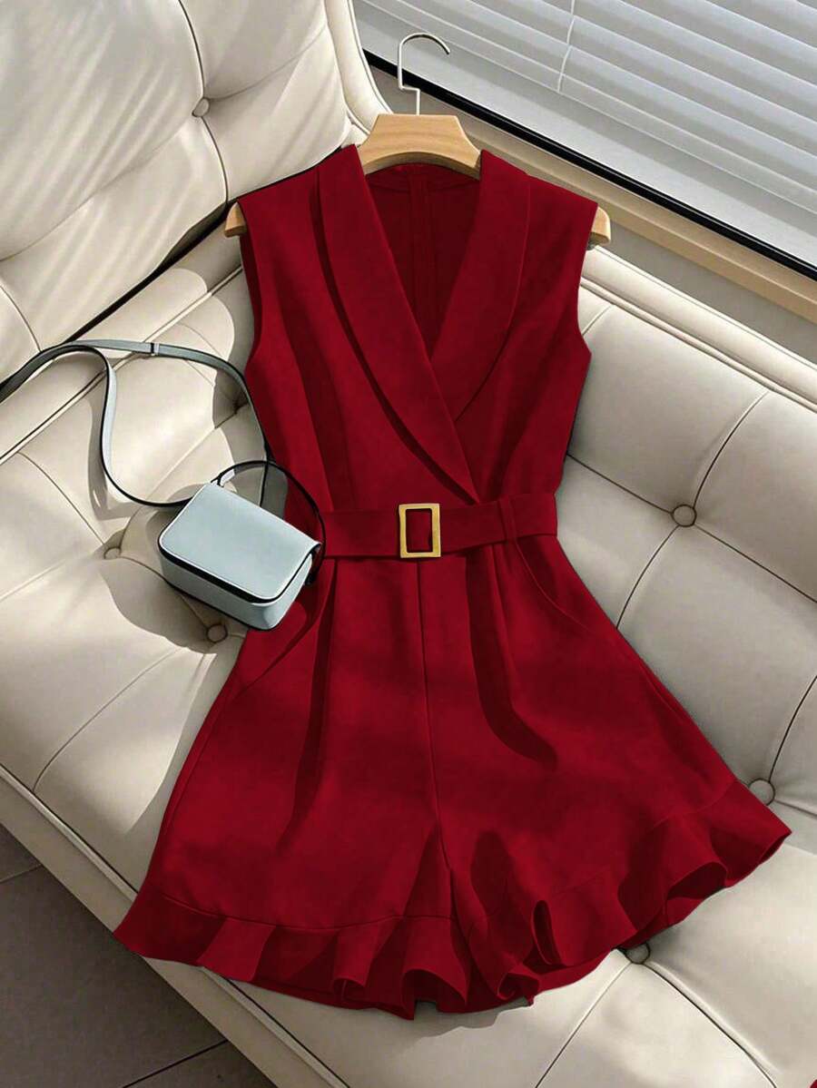 Romper elegante color rojo vino sin mangas con cinturón y escote de solapa, exhibido en un sofá blanco.