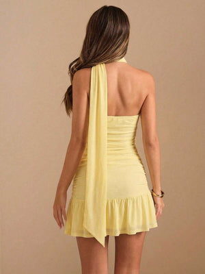 Primer plano del torso de una modelo vistiendo un vestido amarillo con detalle de cuello halter cruzado y textura drapeada.