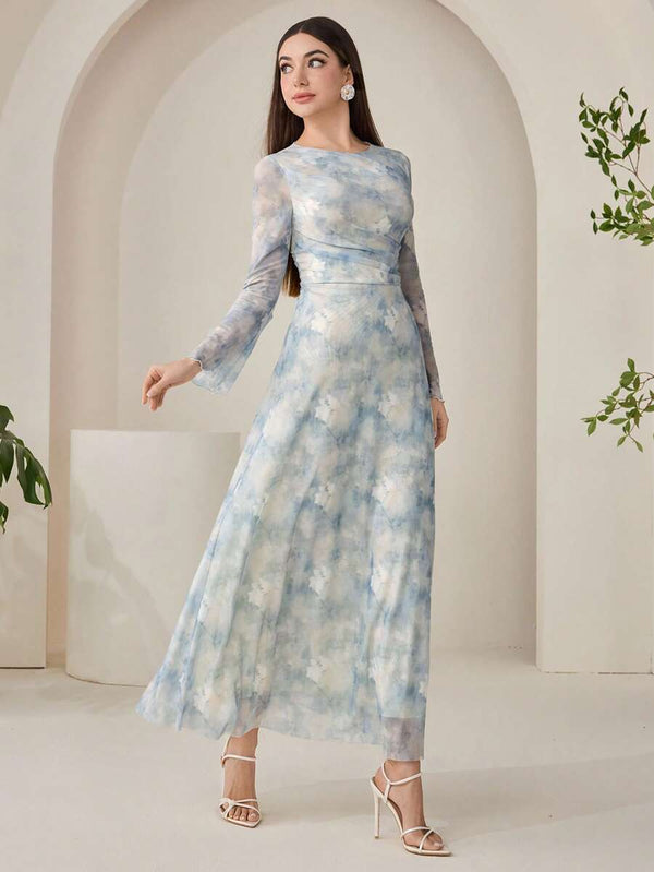 Vista de la parte inferior de un vestido largo estampado, mostrando la fluidez de la falda y sandalias blancas de tacón.