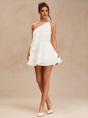 Look completo con vestido blanco corto de un hombro y zapatos a juego.
