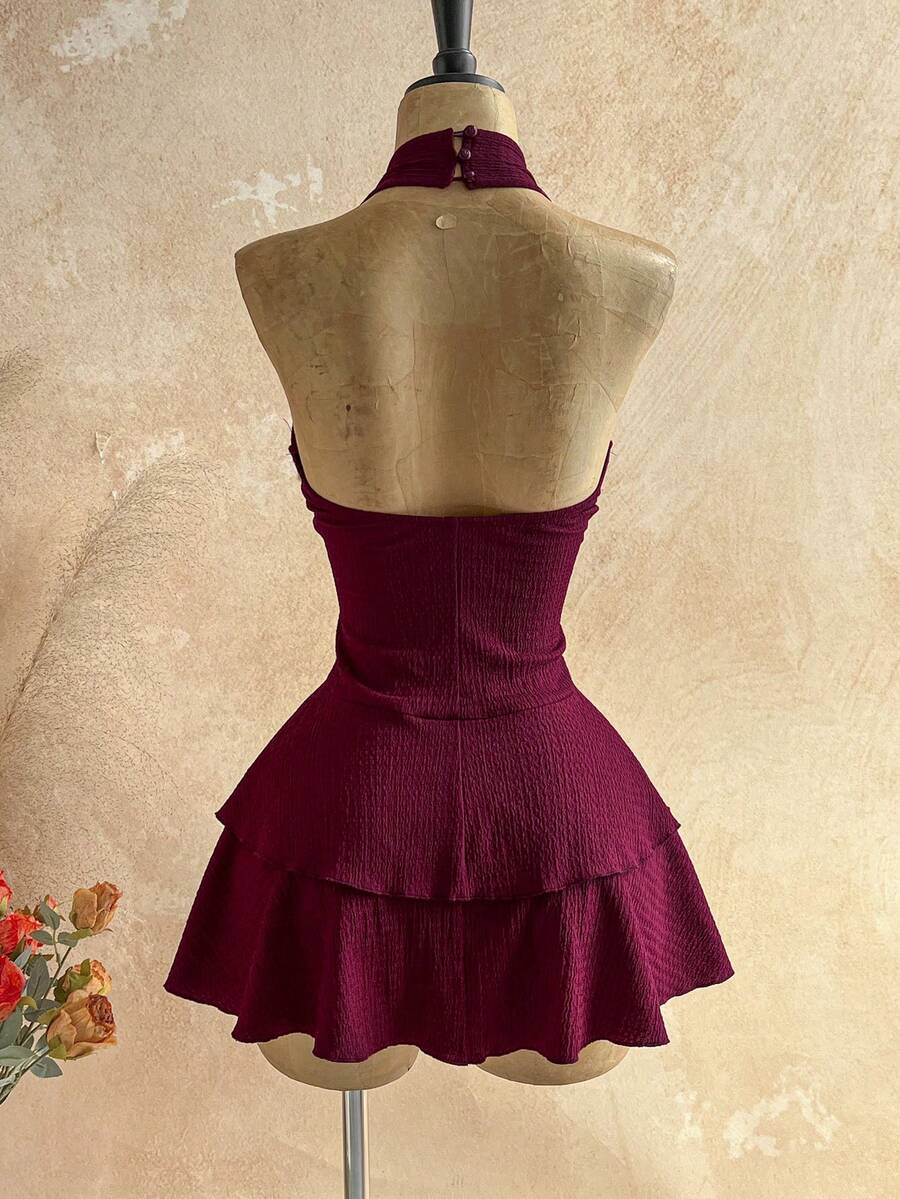 Vista frontal de un vestido corto halter color vino con detalle de estrella de mar y falda de volantes.