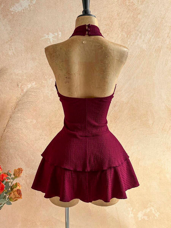 Detalle del escote en V profundo de un vestido halter color vino, mostrando el aplique de estrella de mar en el centro.