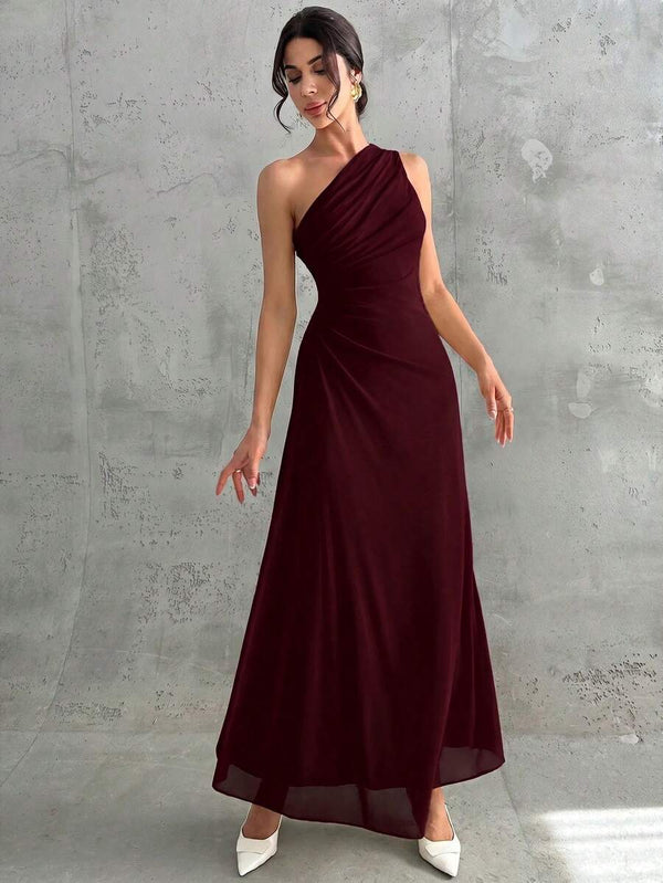 Mujer posando de perfil con un elegante vestido largo de fiesta asimétrico y drapeado.