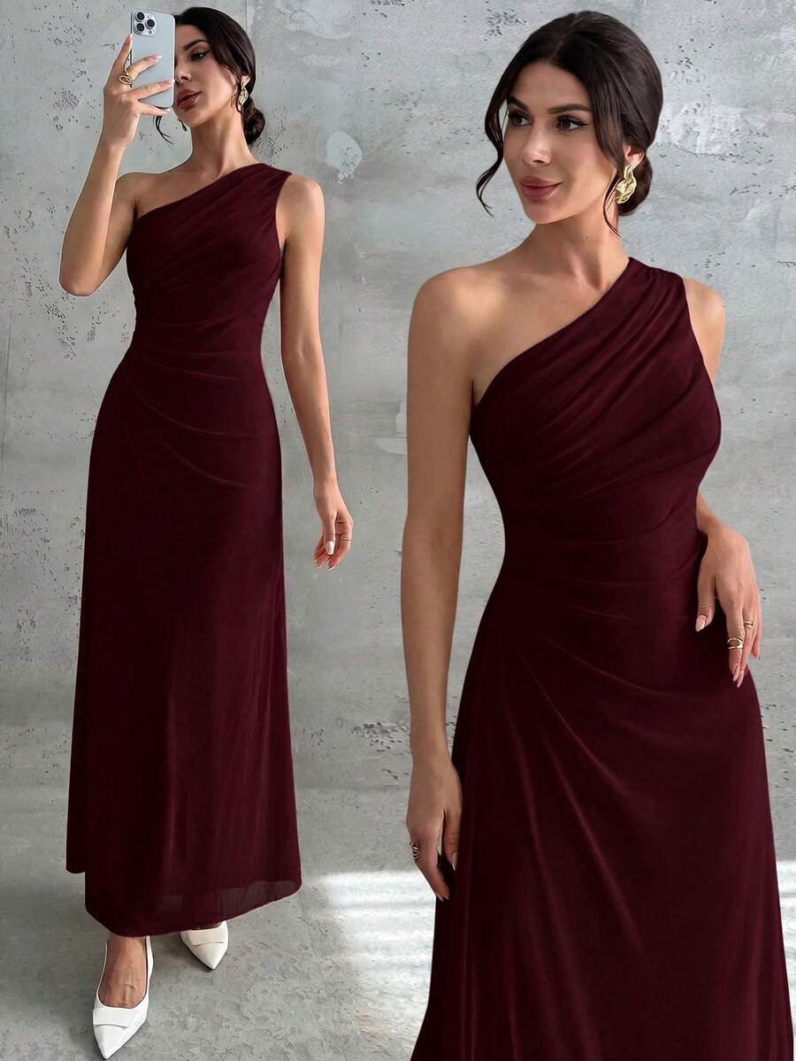 Vista frontal de una mujer usando un vestido largo color vino tinto de un solo hombro con detalle drapeado.
