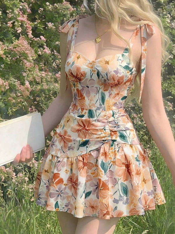 Detalle de la falda con volantes y estampado floral en tonos naranjas de un vestido de verano.