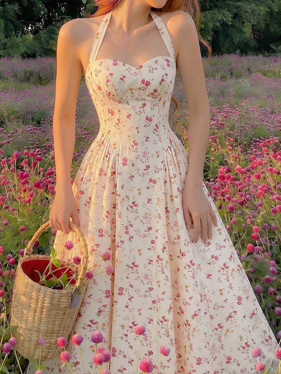 Mujer de espaldas luciendo un vestido floral midi con escote halter en un campo de flores.
