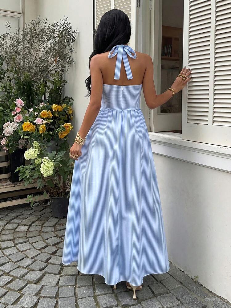 Mujer con vestido midi de rayas azules y blancas con escote halter sentada en un bote.