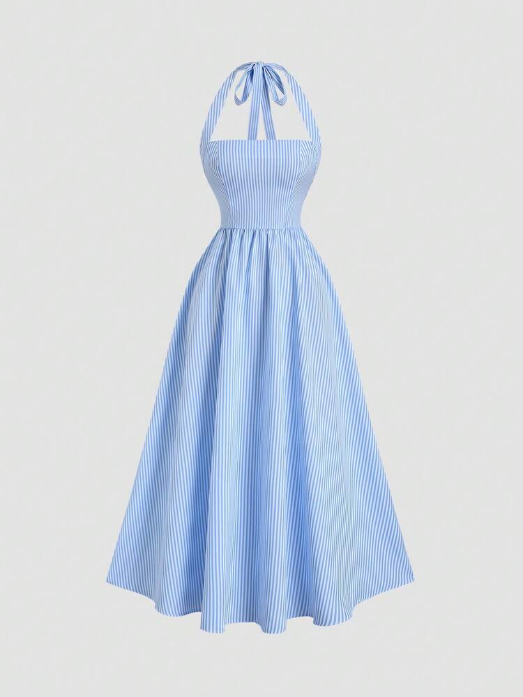 Mujer con vestido midi de rayas azules y blancas con escote halter sentada en un bote.