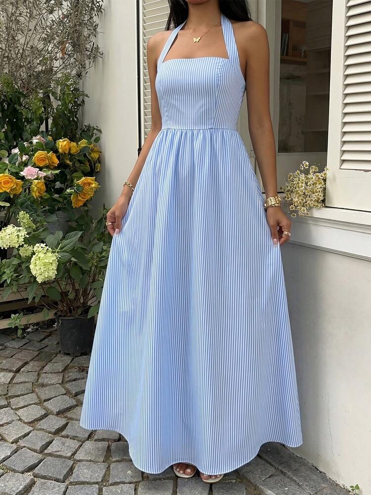 Mujer con vestido midi de rayas azules y blancas con escote halter sentada en un bote.