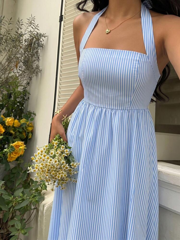 Mujer con vestido midi de rayas azules y blancas con escote halter sentada en un bote.