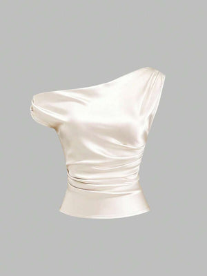 Detalle del drapeado y fruncido lateral en blusa satinada asimétrica color crema