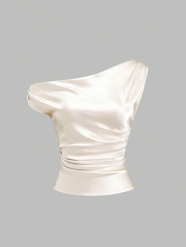 Detalle del drapeado y fruncido lateral en blusa satinada asimétrica color crema