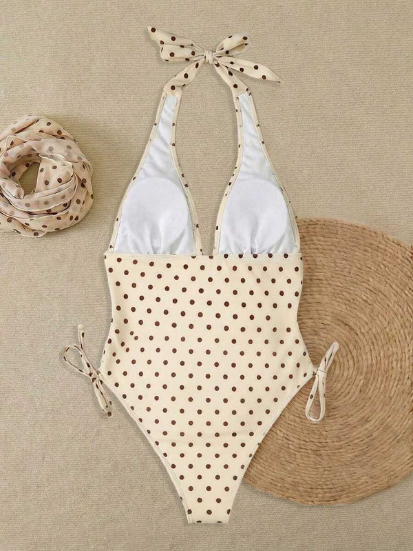 Vista frontal de un traje de baño de una pieza con estampado de polka dots y lazos laterales ajustables.