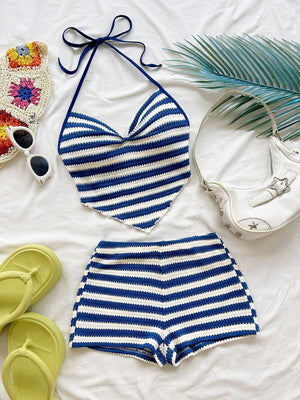 Conjunto de dos piezas de crochet con rayas azules y blancas, compuesto por un top halter y shorts, mostrado en un flat lay con accesorios de verano.