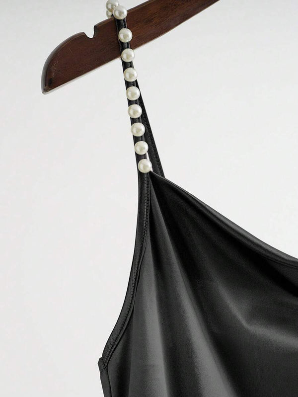 Primer plano de los tirantes de perlas artesanales del jumpsuit negro.