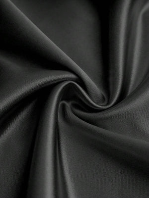 Vista inferior de los pantalones de pierna ancha del jumpsuit negro, mostrando su caída y fluidez.