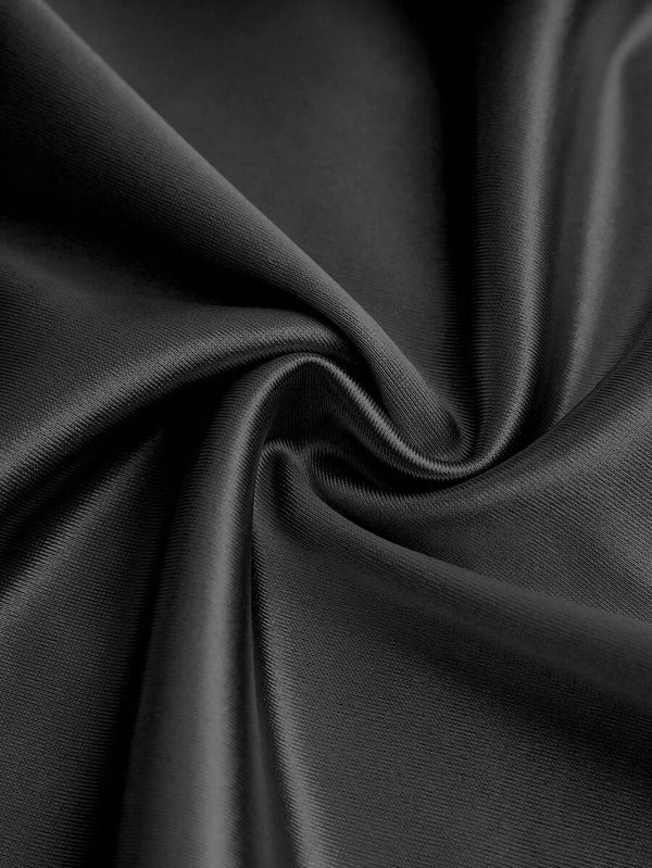 Vista inferior de los pantalones de pierna ancha del jumpsuit negro, mostrando su caída y fluidez.
