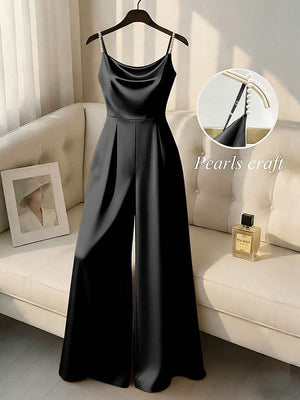 Jumpsuit negro elegante de pierna ancha con tirantes de perlas colgado en una percha.