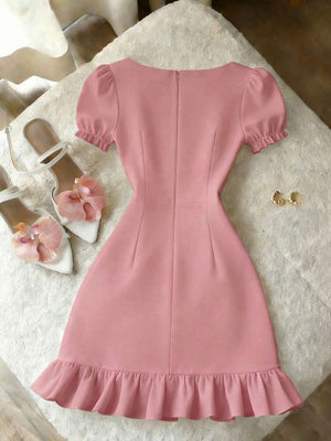 Detalle del escote cuadrado y manga abullonada de un vestido rosa.