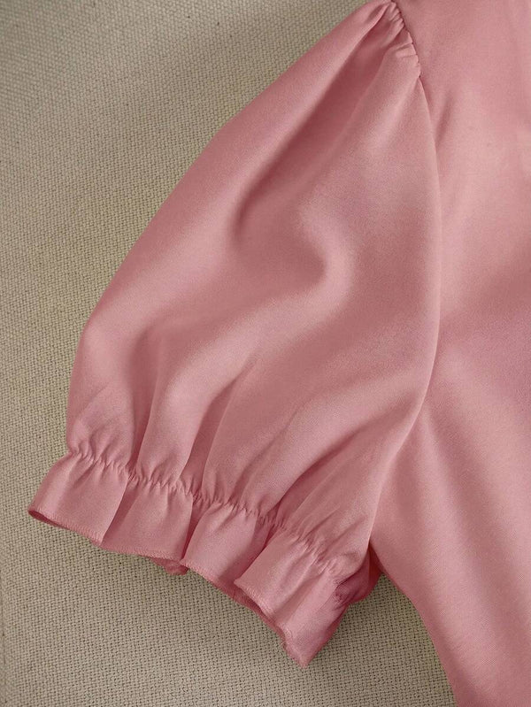 Primer plano de la falda corta en línea A con bajo de volantes del vestido rosa.