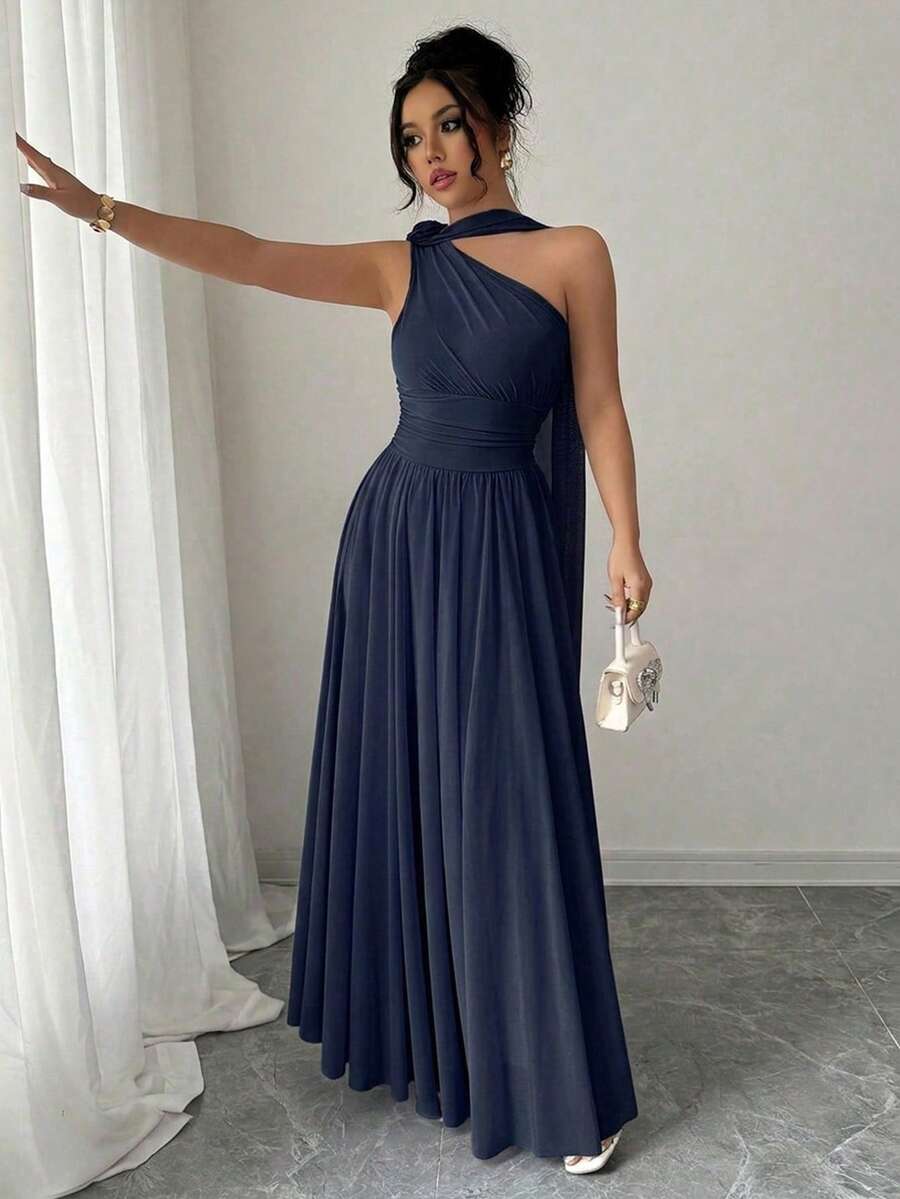 Mujer con vestido largo azul marino de un hombro posando frente a un espejo.