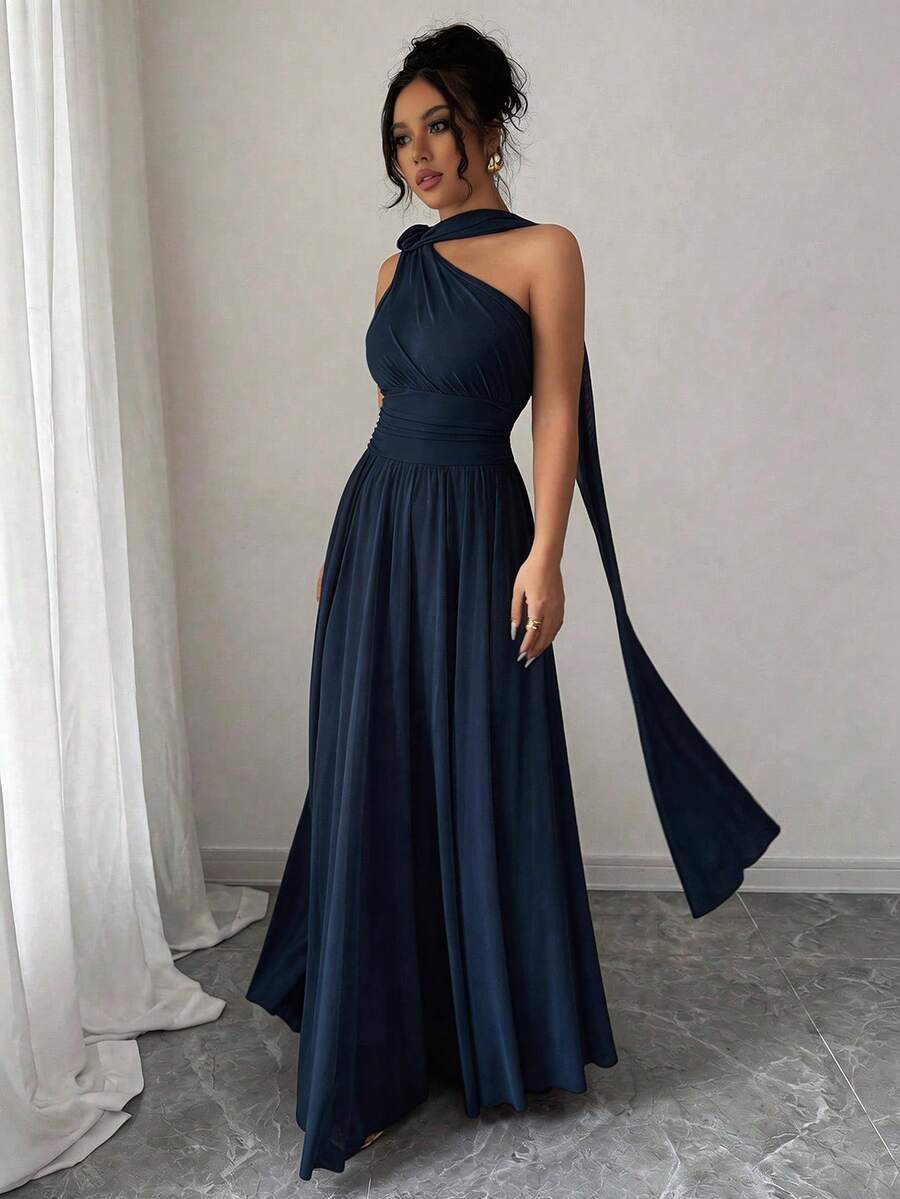 Mujer con vestido largo azul marino de un hombro posando frente a un espejo.