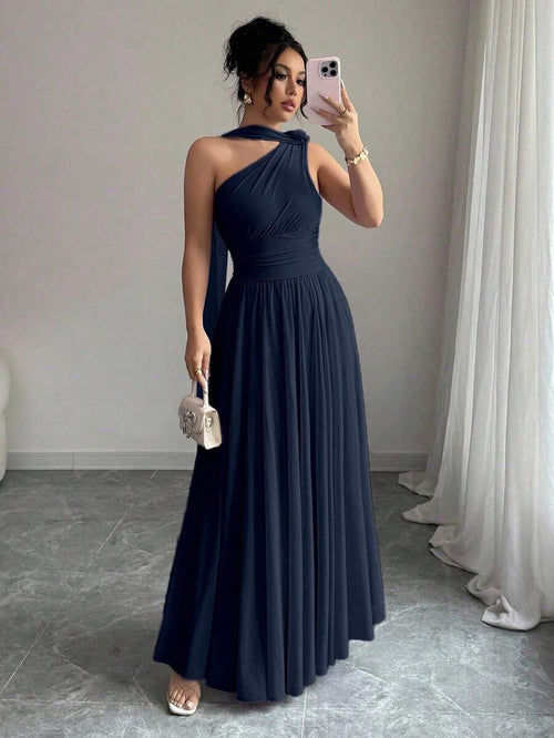 Mujer con vestido largo azul marino de un hombro posando frente a un espejo.