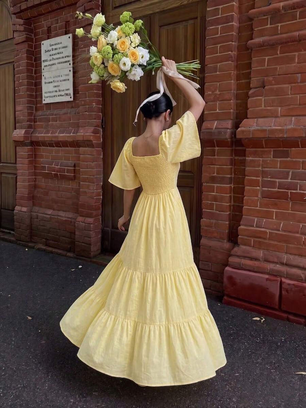 Look completo de vestido maxi amarillo con bolso de paja en la arena.