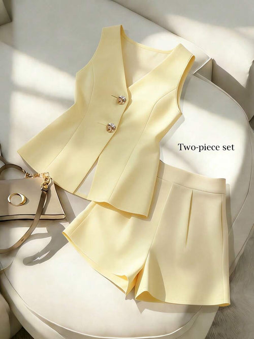 Conjunto elegante de chaleco y short amarillo pálido sobre un sillón blanco.