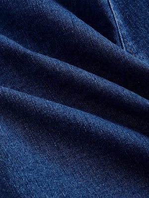 Primer plano de los botones dorados ornamentados en un chaleco top de mezclilla azul.