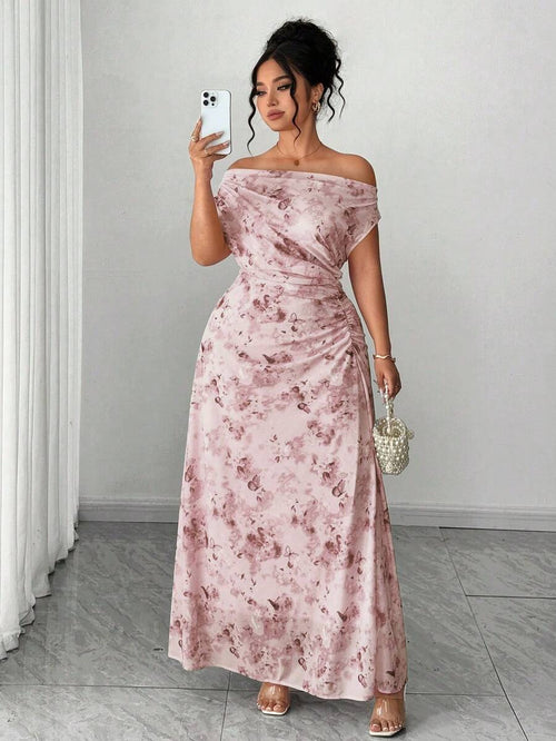 Mujer posando con un vestido largo rosa de hombros descubiertos y estampado de mariposas.