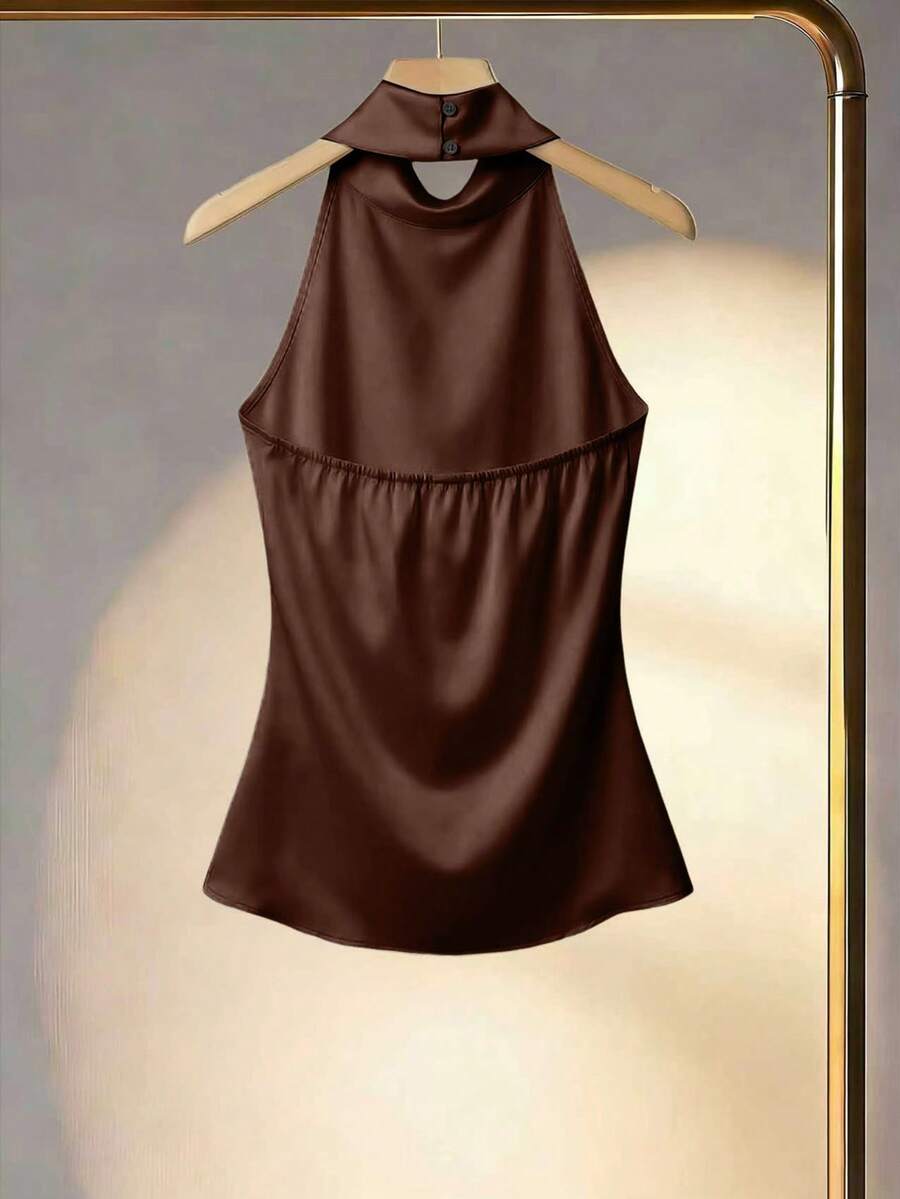 Top halter satinado de color marrón chocolate colgado en una percha dorada, vista frontal.