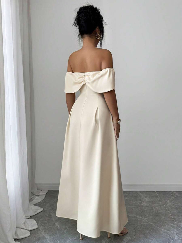 Primer plano del escote bardot con lazo de un vestido de fiesta color crema.
