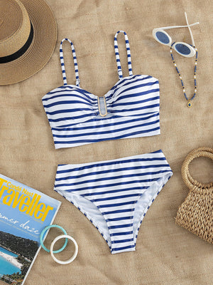 Vista superior de un conjunto de bikini de dos piezas a rayas azules y blancas sobre un fondo de tela de yute.