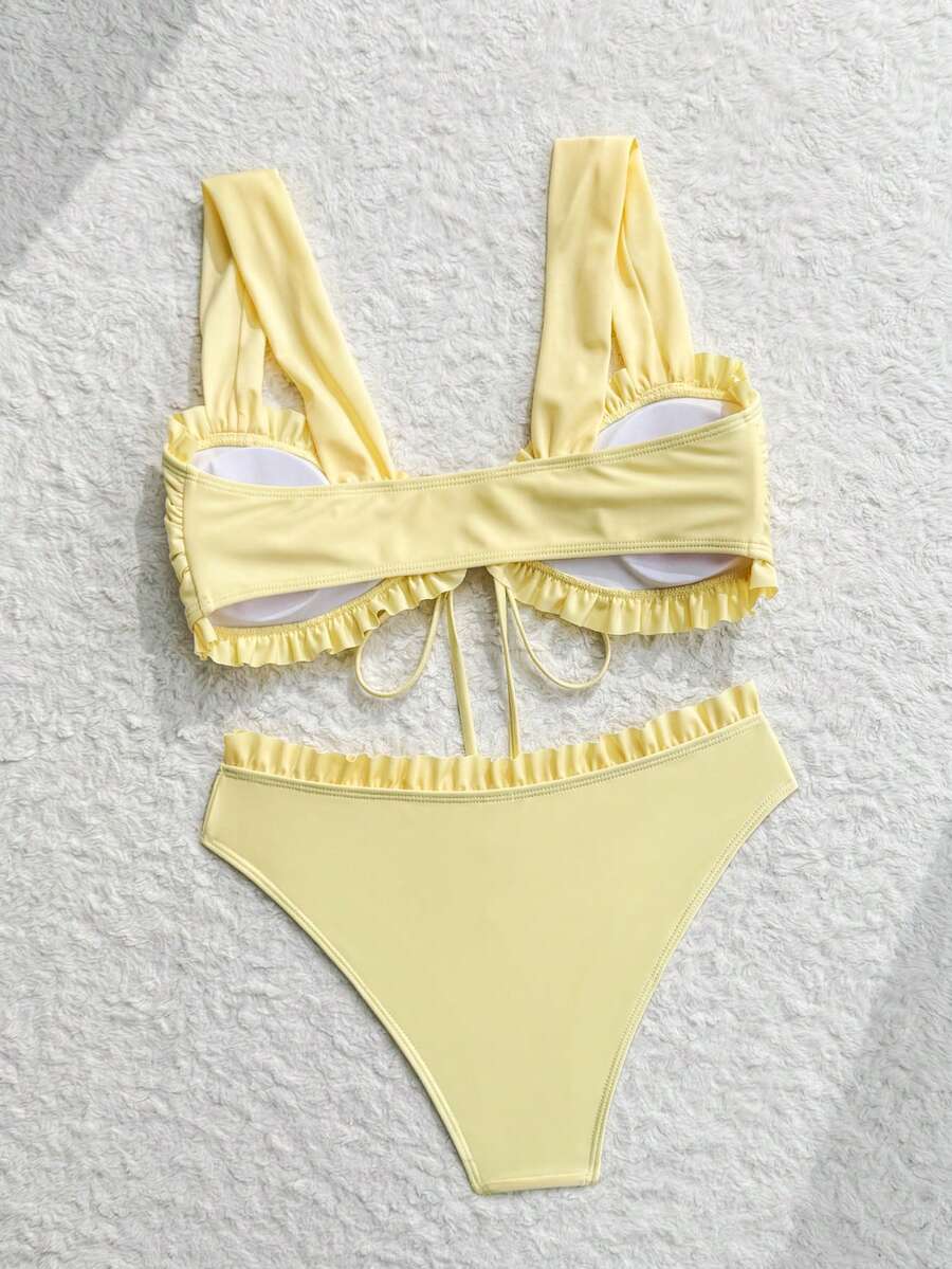 Mujer en la playa vistiendo un bikini amarillo de dos piezas con volantes.
