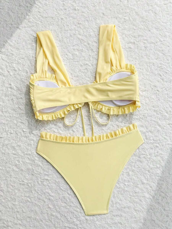 Detalle del top de bikini amarillo con lazo frontal y volantes en el escote.