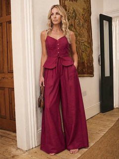 Vista completa de mujer vistiendo un conjunto de dos piezas color burdeos con top peplum y pantalón de pierna ancha.