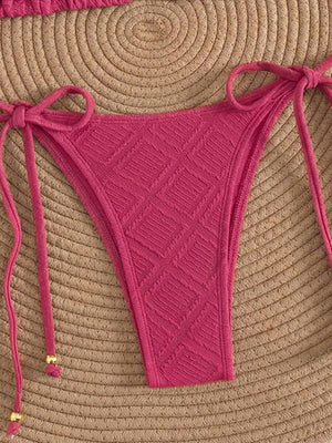 Conjunto de bikini de dos piezas en color rosa fucsia con detalles de pompones dorados.