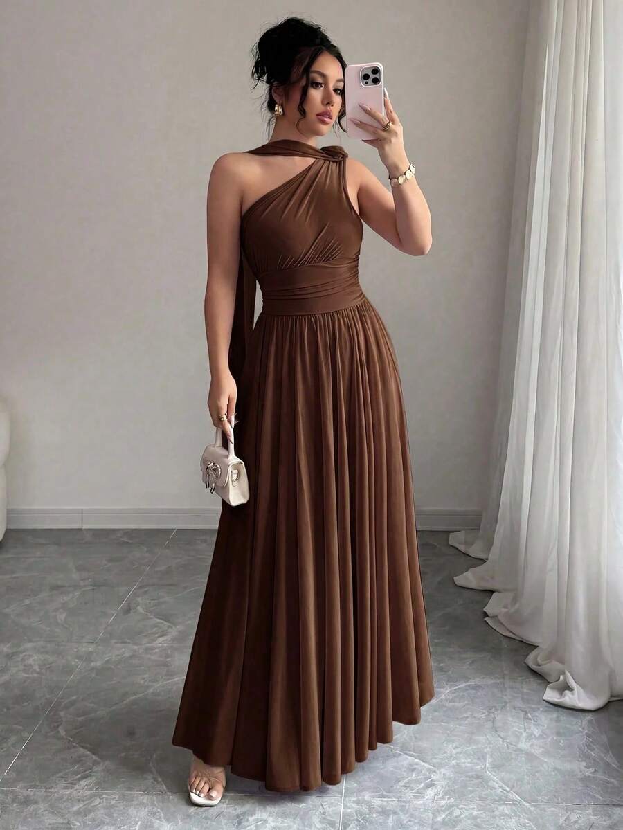 Mujer posando con un vestido largo marrón asimétrico de un solo hombro.