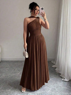 Mujer posando con un vestido largo marrón asimétrico de un solo hombro.