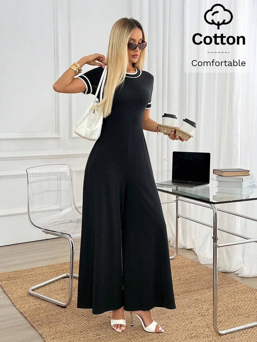 Mujer elegante vistiendo un jumpsuit negro de pierna ancha y manga corta en una oficina.