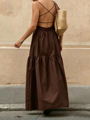 Primer plano de la falda larga con volantes de un vestido bohemio color café y un bolso de paja.
