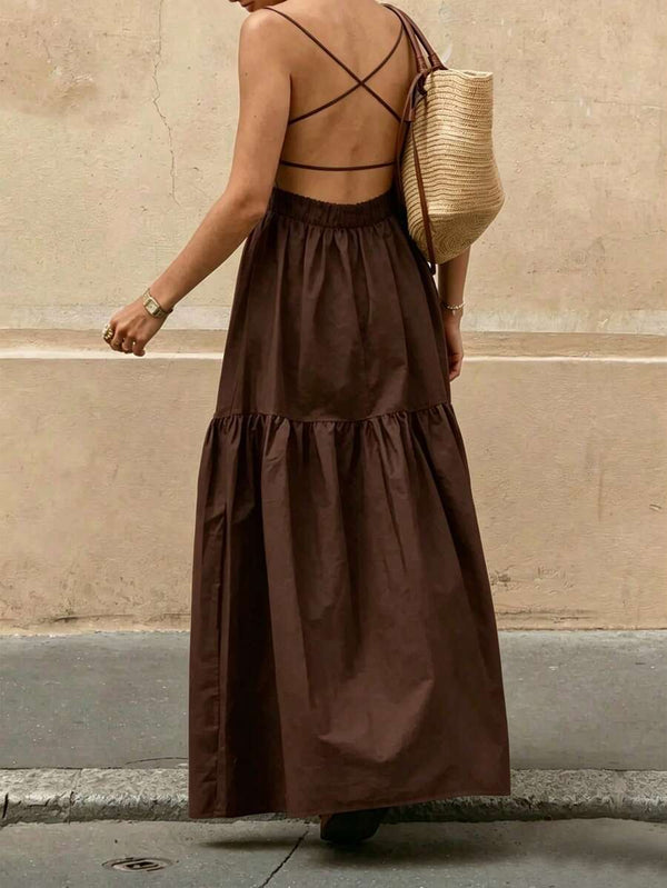 Primer plano de la falda larga con volantes de un vestido bohemio color café y un bolso de paja.
