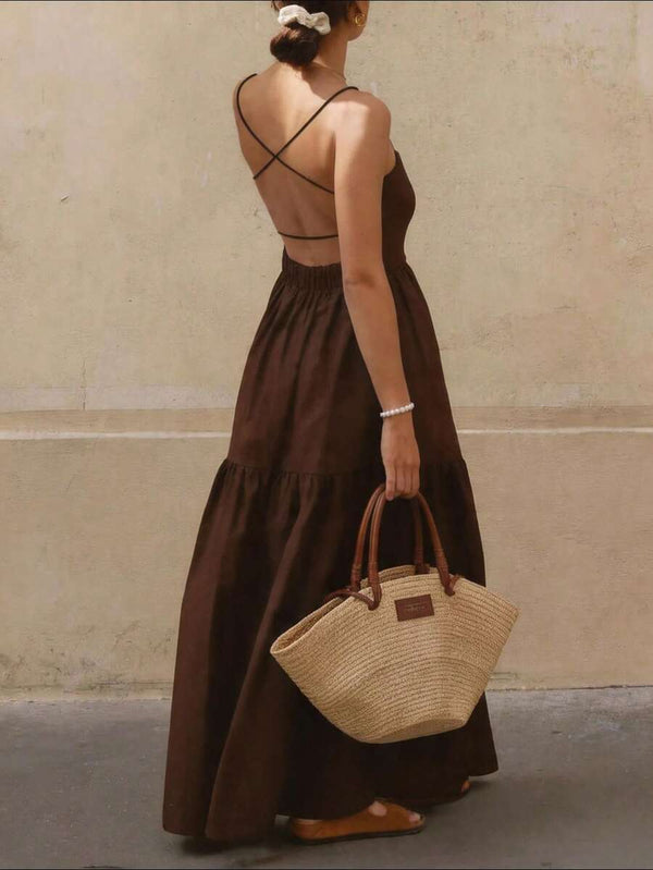 Vista trasera de una mujer usando un vestido maxi color café con espalda descubierta y tirantes finos cruzados.