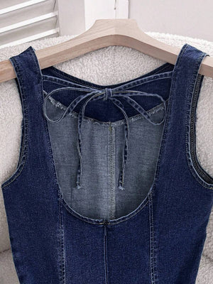 Parte inferior de un vestido de mezclilla con falda acampanada, junto a unos zapatos planos negros en el suelo.