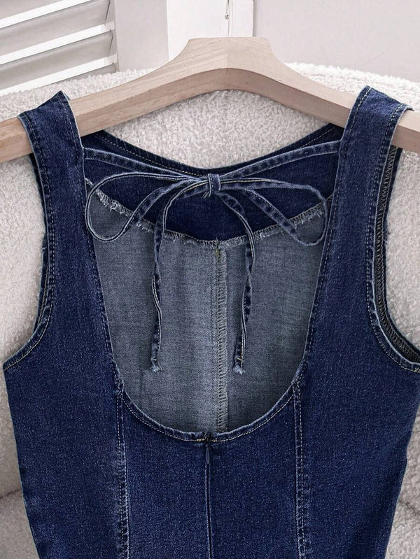 Parte inferior de un vestido de mezclilla con falda acampanada, junto a unos zapatos planos negros en el suelo.