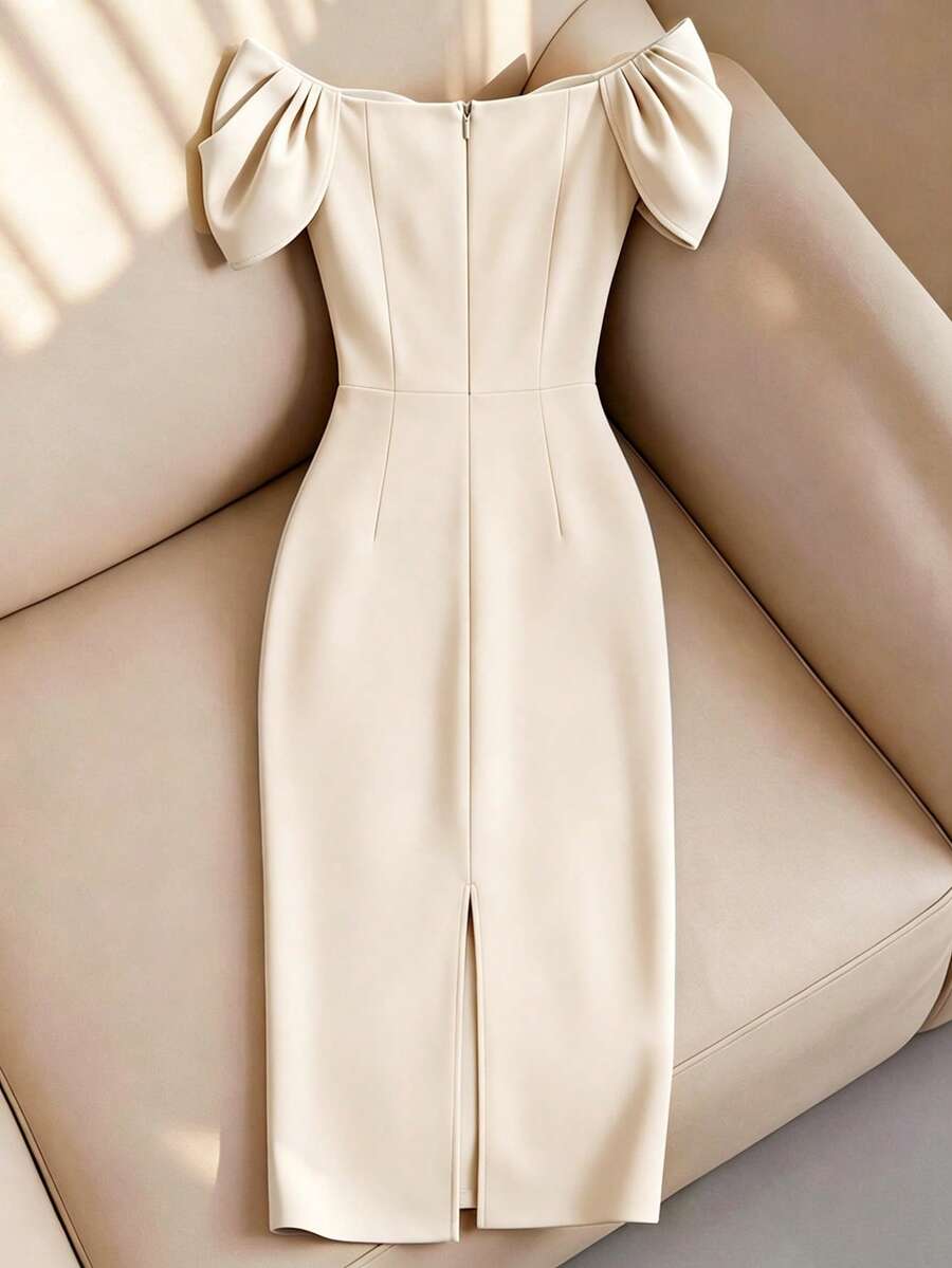Vestido elegante color crema con hombros descubiertos y corte sirena exhibido en un sofá.
