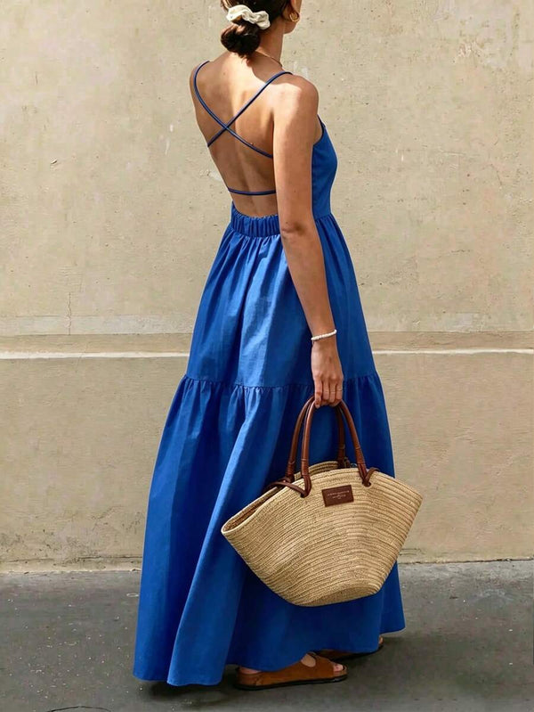 Vista trasera de una mujer usando un vestido maxi azul rey con espalda descubierta y tirantes cruzados.
